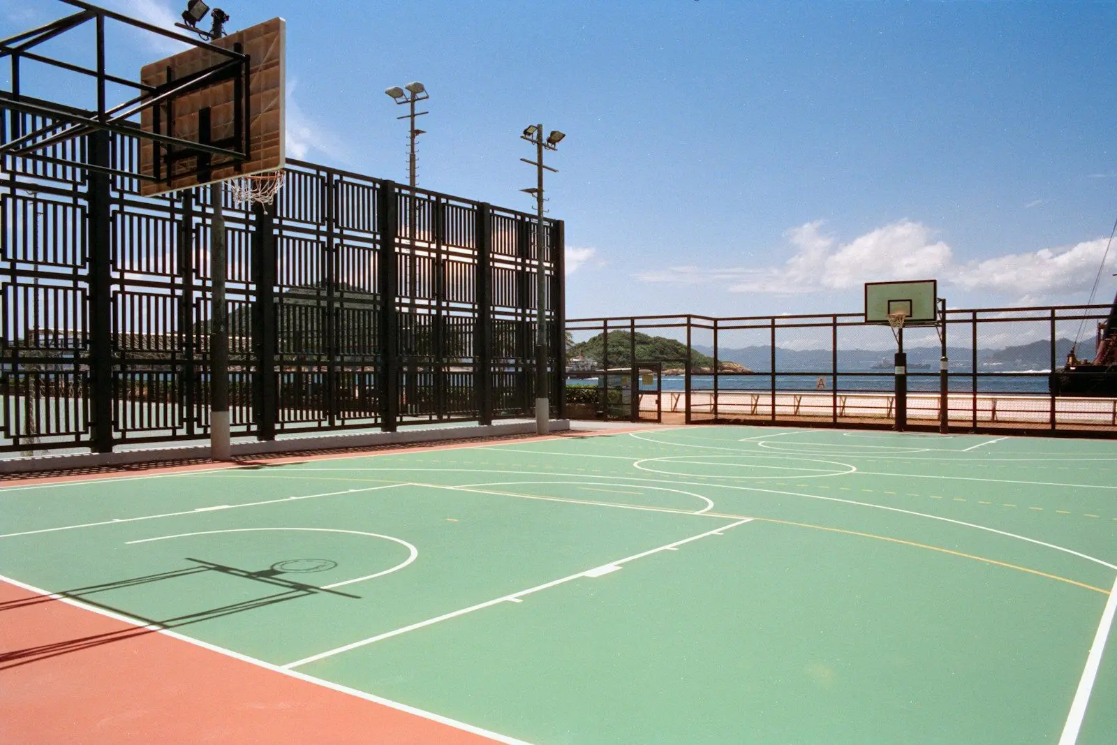 Fenced outdoor multi-sport court with basketball hoops and line markings